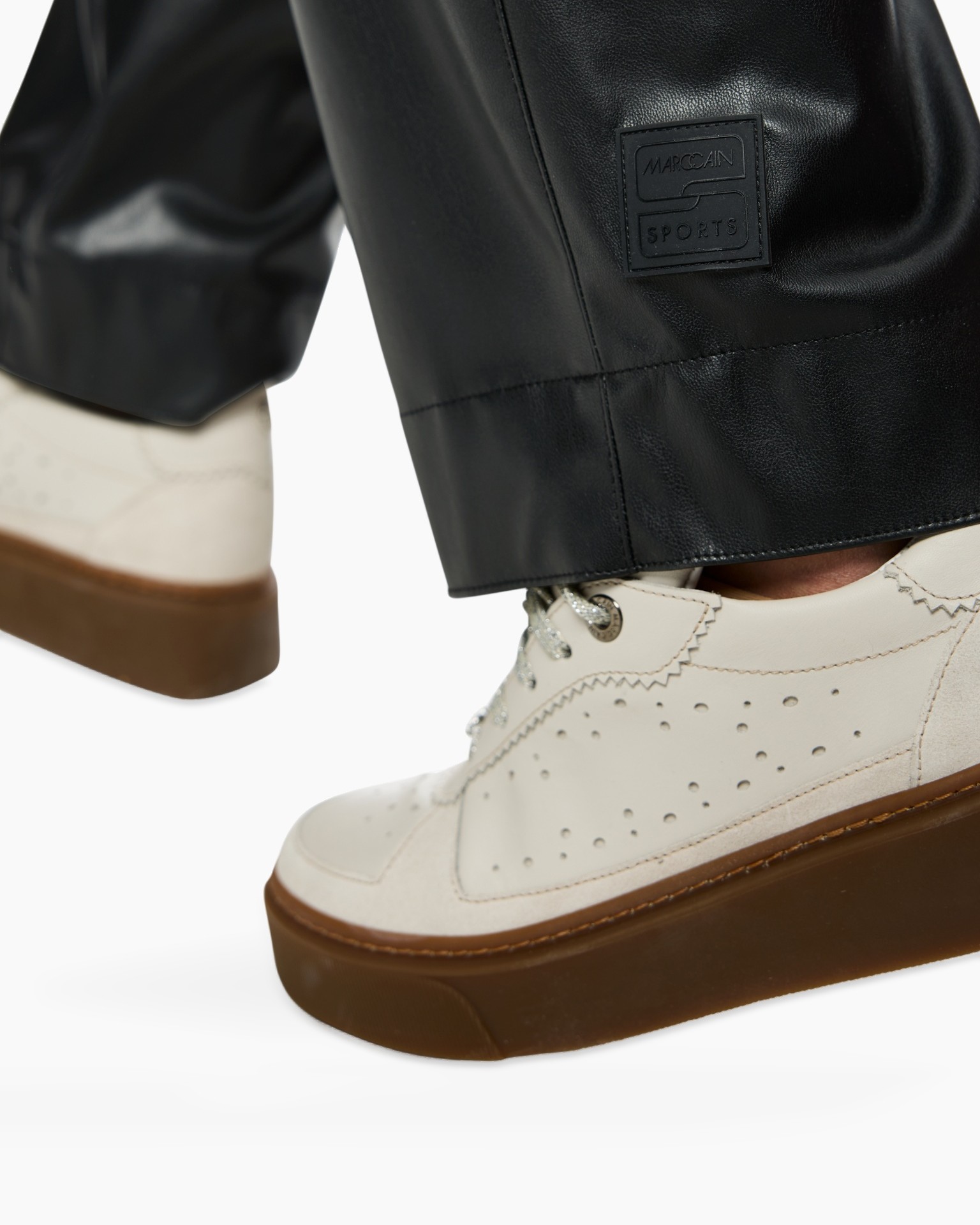 leather pants, black pants, flag patch?, brand label on cuff, white sneaker, grommet holes