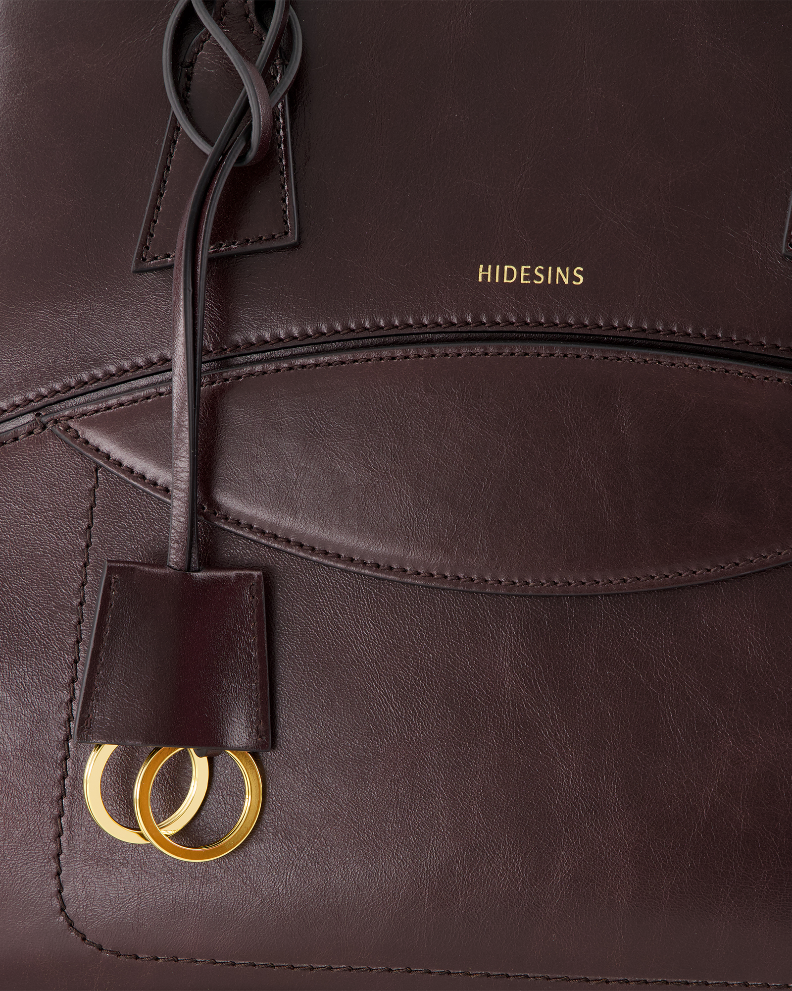 leather bag, brown, gold rings, stitching, brand wordmark