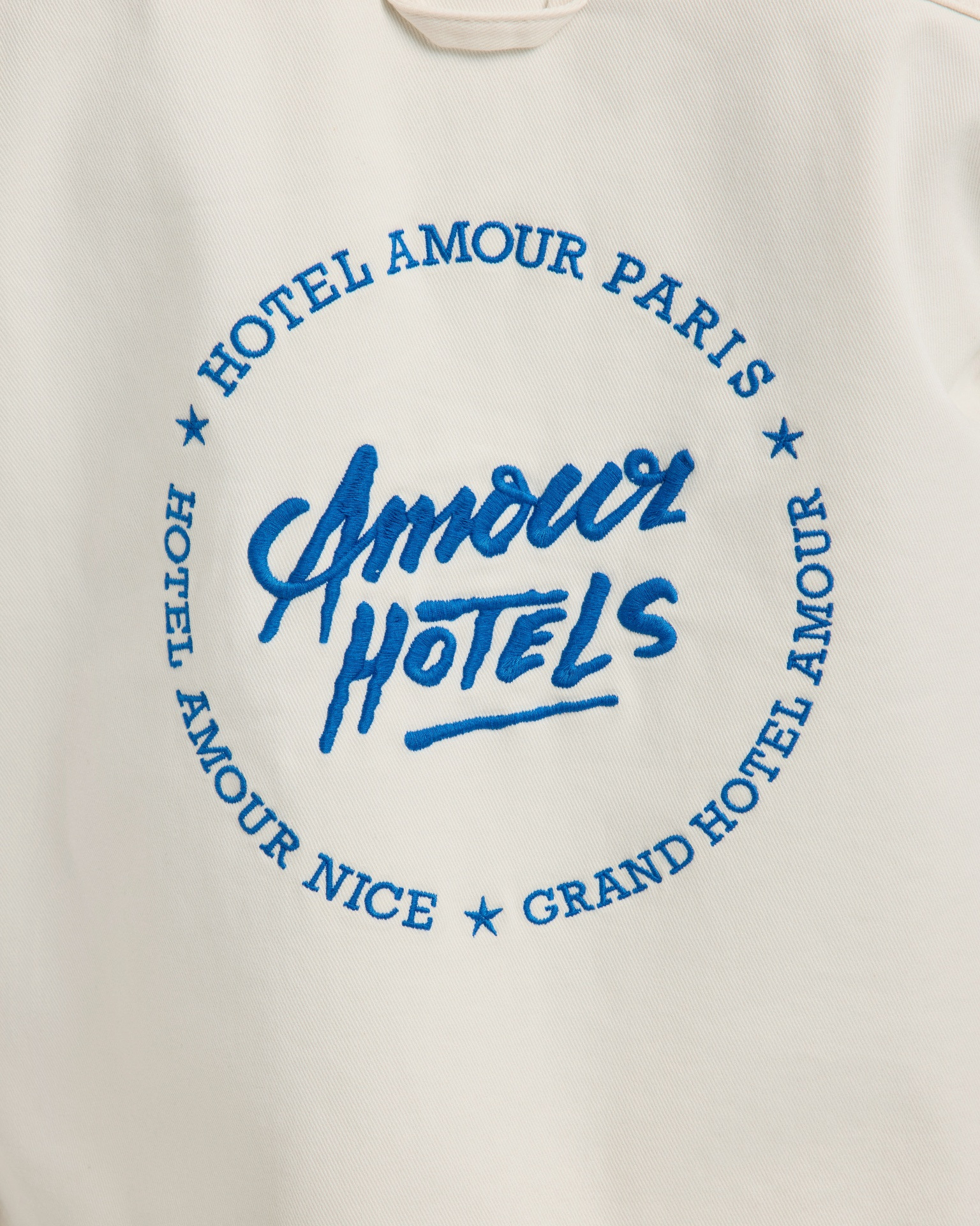 graphic tee, round logo, blue text, white fabric, hotel motif