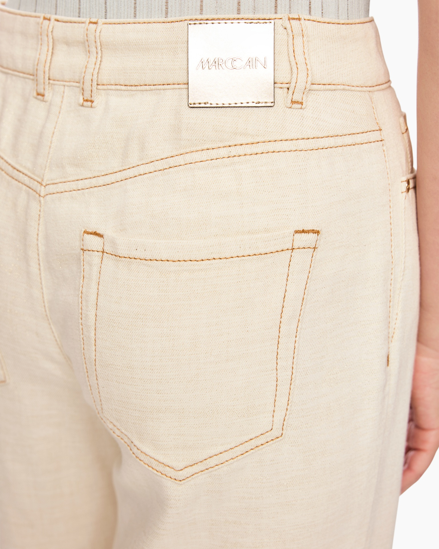 beige pants, back pocket, jeans stitching, belt loop, metal logo